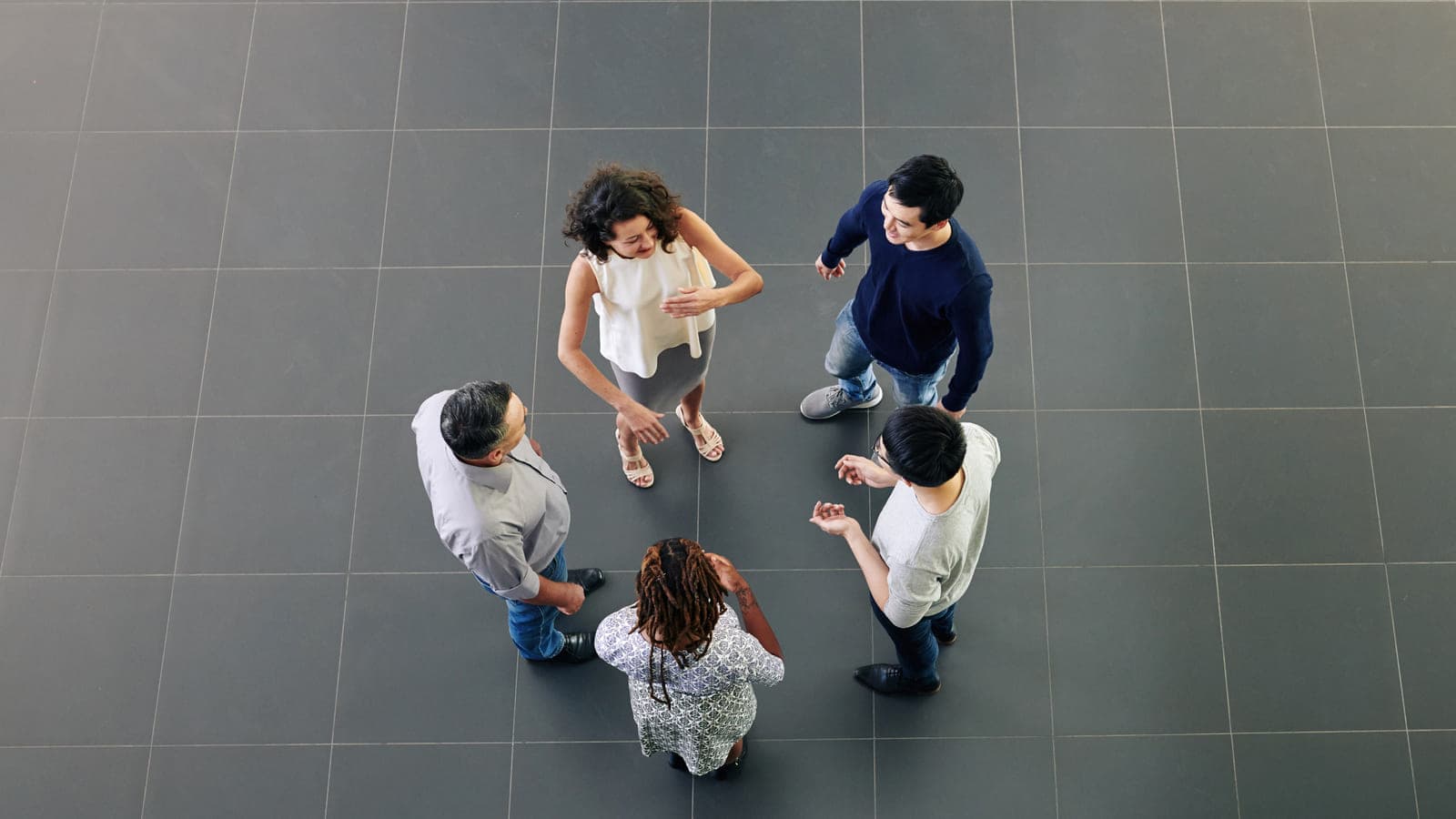 Fünf Menschen stehen im Kreis und sprechen miteinander, von oben gesehen